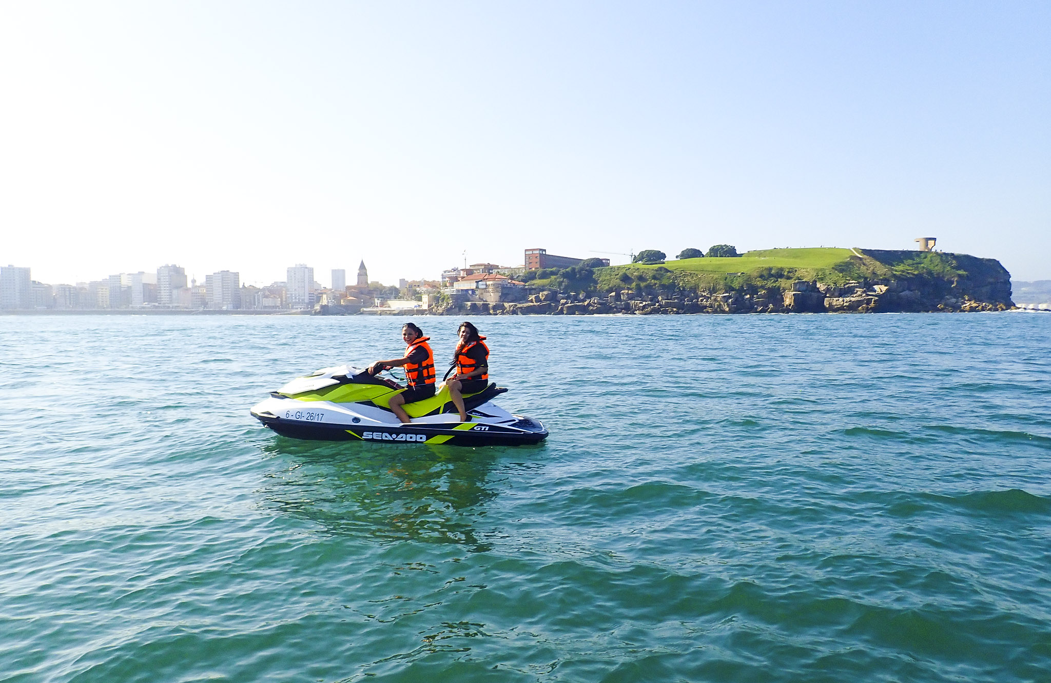 Ruta en moto de agua por las Rías Baixas Dos clientas disfrutando en una moto de agua frente a la costa de Sanxenxo en un día soleado de verano.