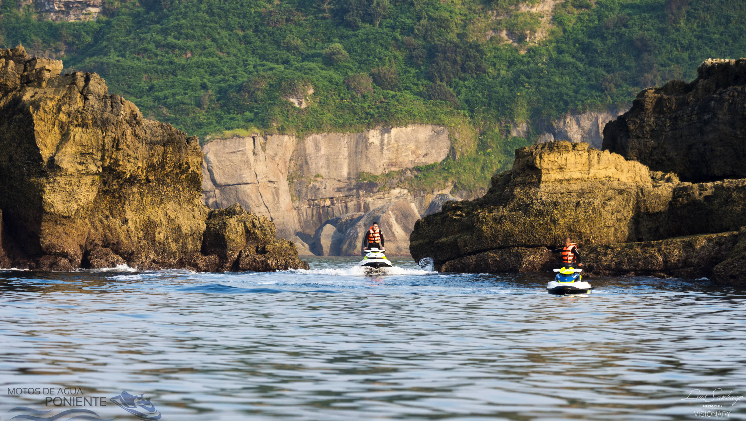 Dos motos de agua navegando entre rocas en la costa de Santander, Cantabria, con el mar Cantábrico de fondo.