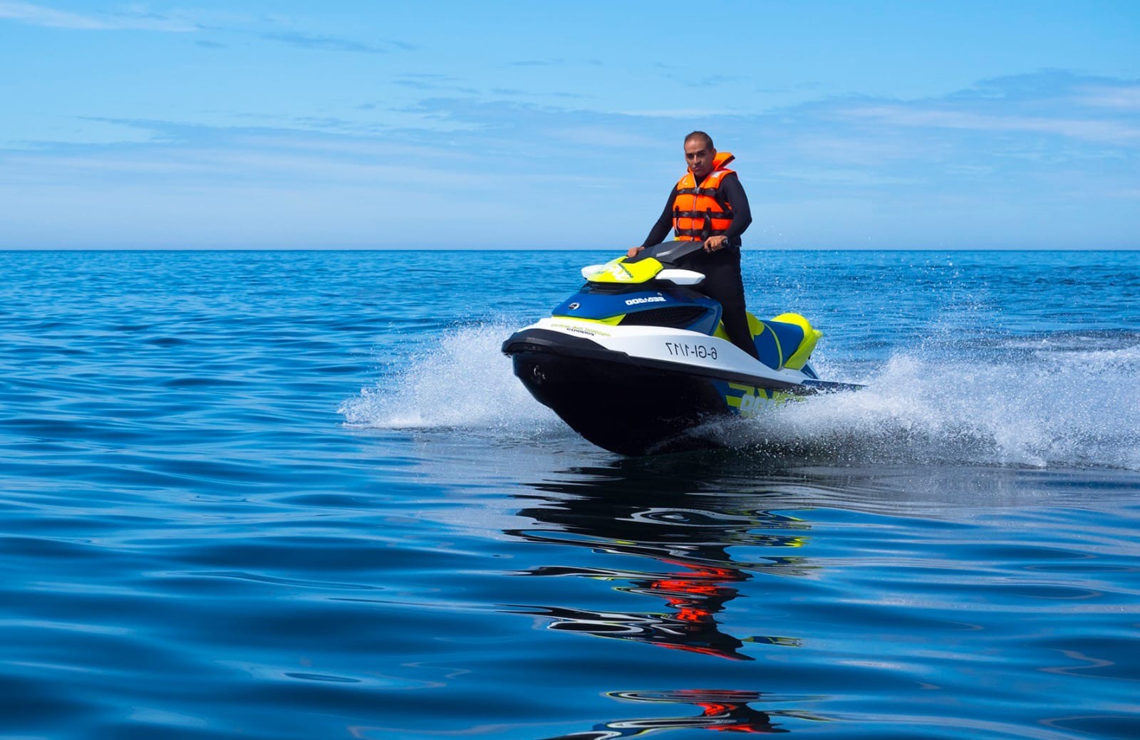 Persona disfrutando de pasear en moto de agua en el mar en un día soleado y despejado